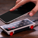 A smartphone being placed atop the 8BitDo N30 Wireless Charger for Mobile sitting on a wood desk.